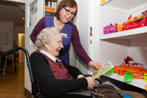 Carer holding book for elderly lady