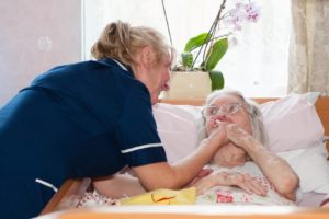 Carer holding elderly lady's hand